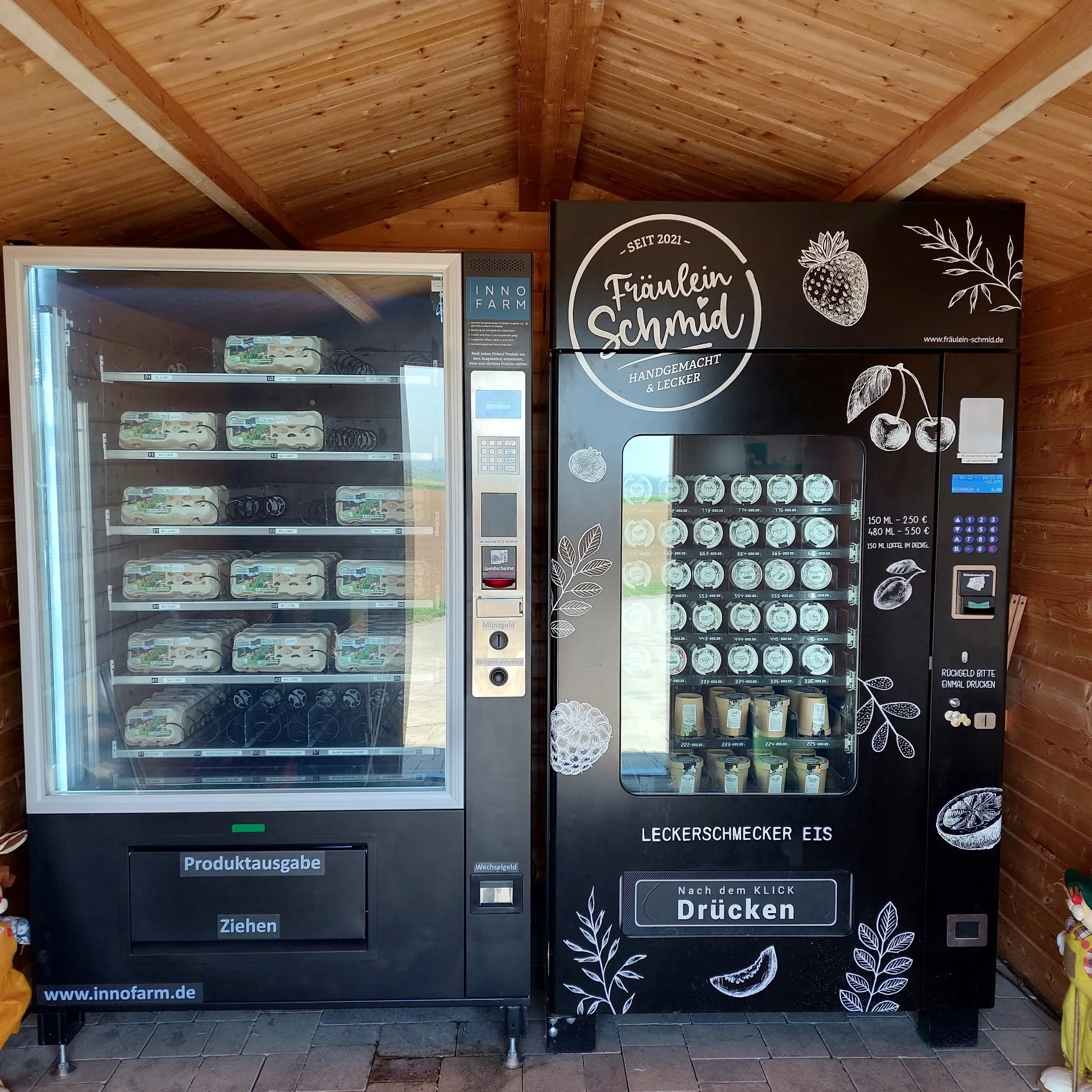 Zwei Verkaufsautomaten im hölzernen Eierhäusle: links der Eier- und Produktautomat, rechts der Eisautomat.